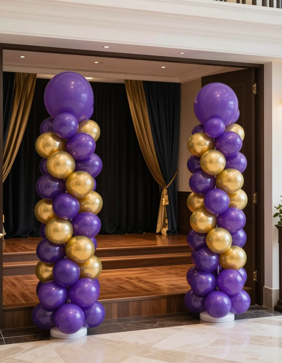 Elegant balloon columns in purple and gold flanking a stage