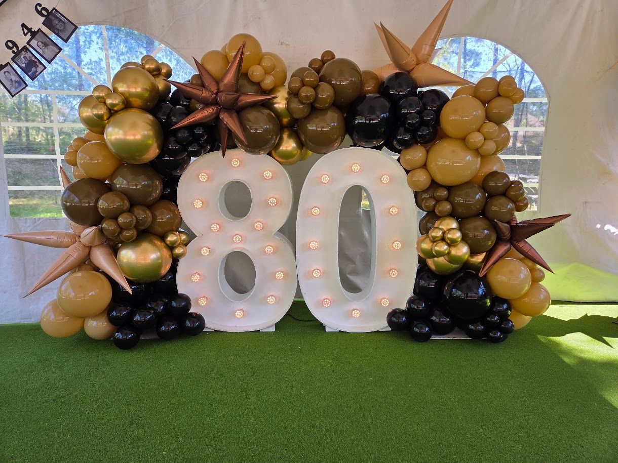 Purple and gold balloon columns framing a stage at an indoor event