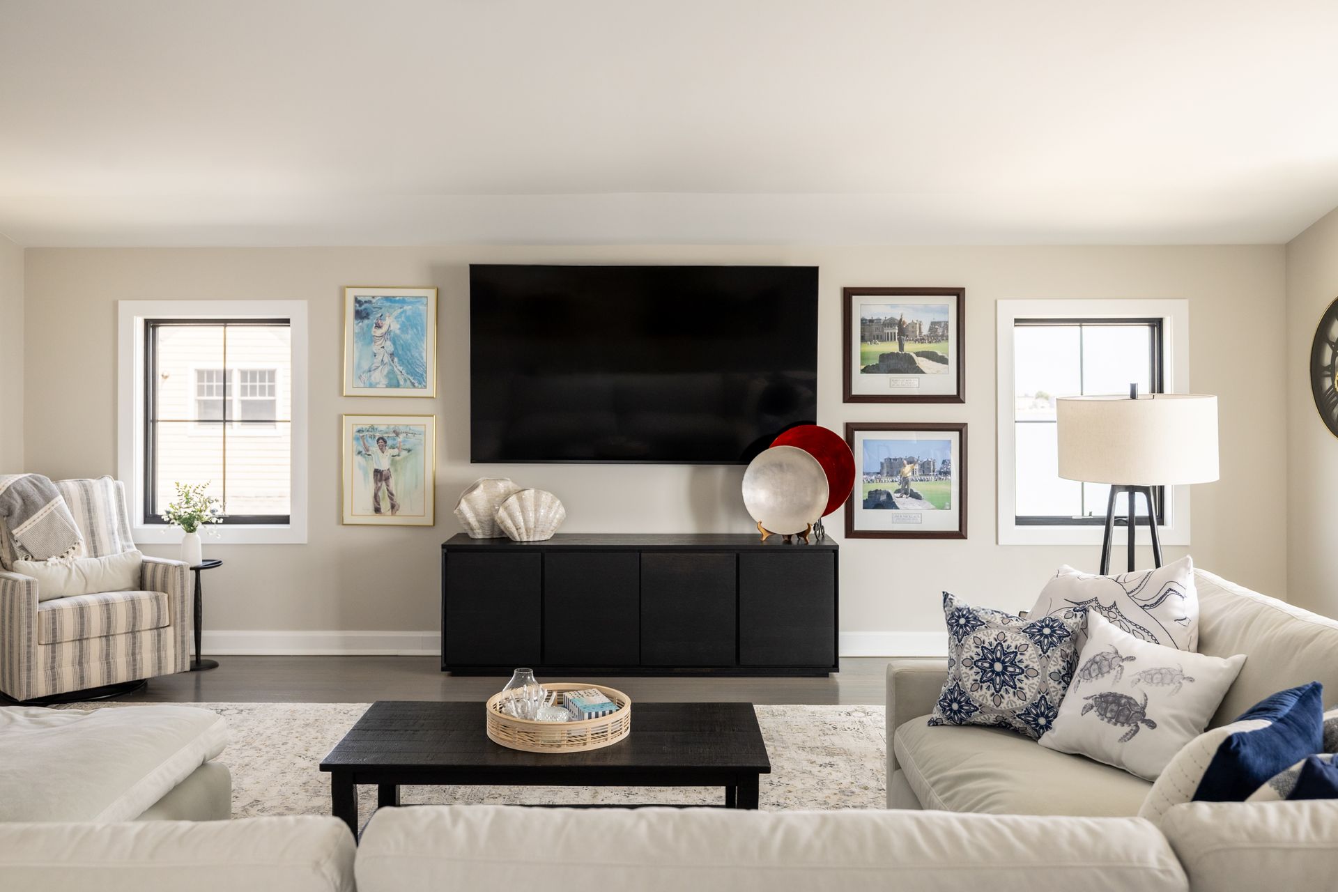 Living room with neutral walls, black TV, black cabinet, and cream-colored furniture.