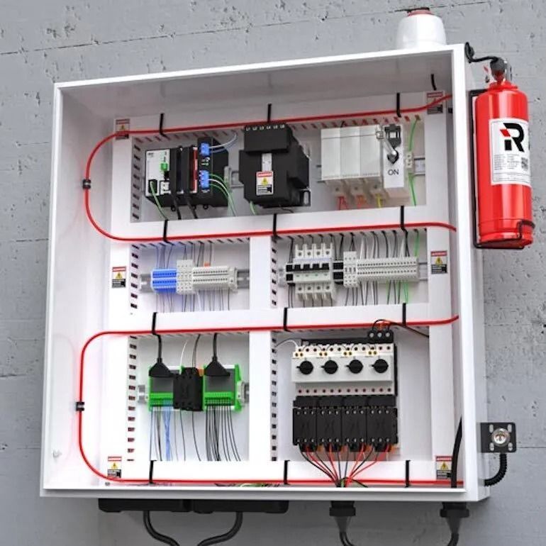 Electrical control panel mounted on a wall with internal wiring, electronic components, and an attached fire extinguisher.