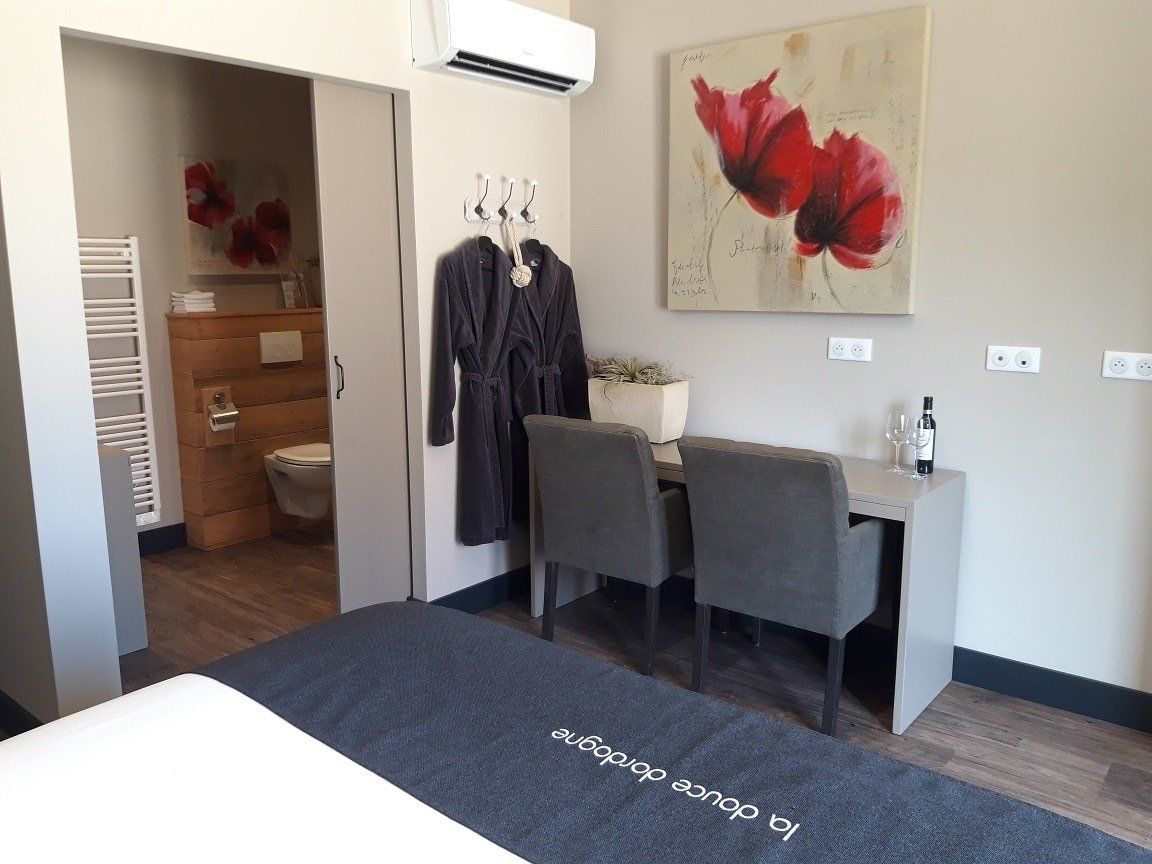 Moderne hotelkamer met twee grijze stoelen, een bureau, muurdecoratie en een bed op de voorgrond.