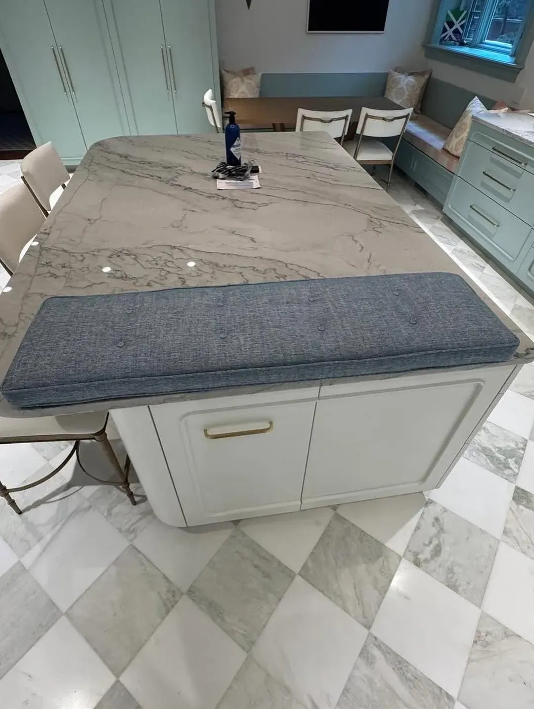 Kitchen island with marble-look countertop, gray runner, and light blue cabinets on a patterned tile floor