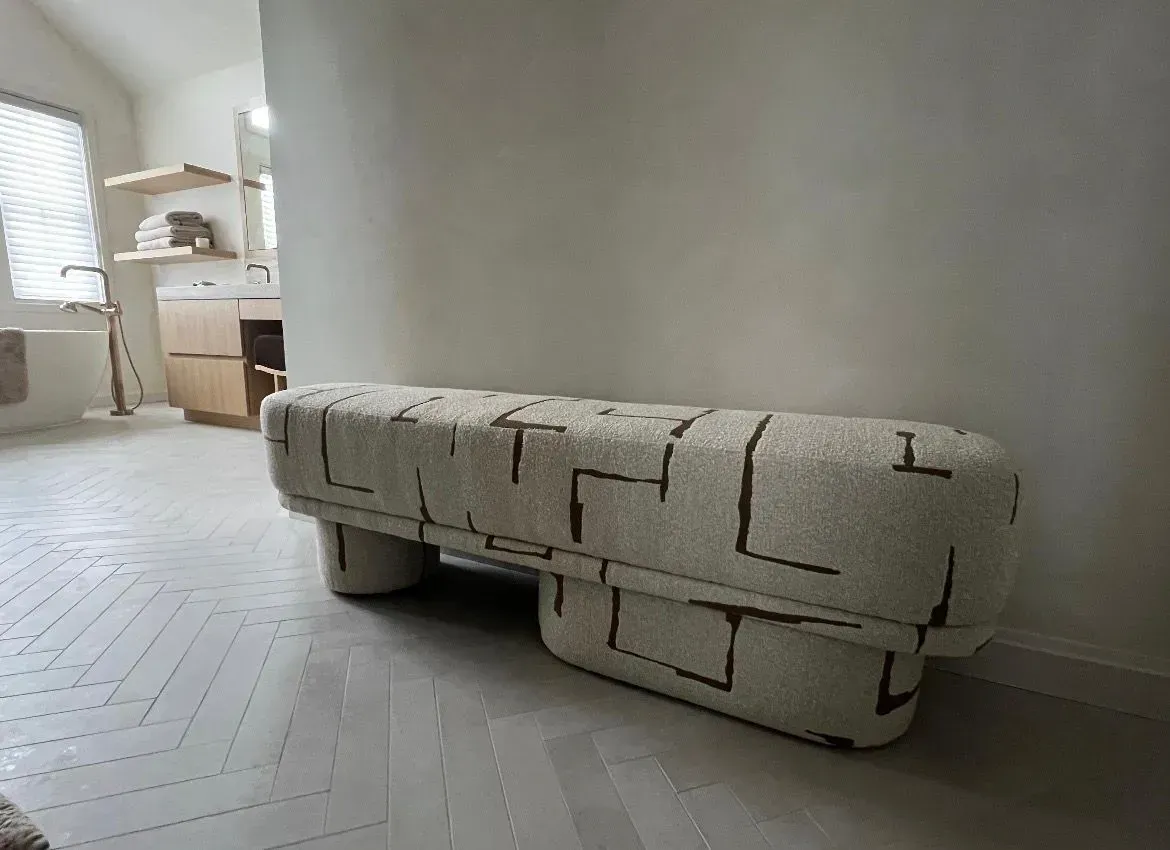 White upholstered bench in a bright hallway with a kitchen visible in the background