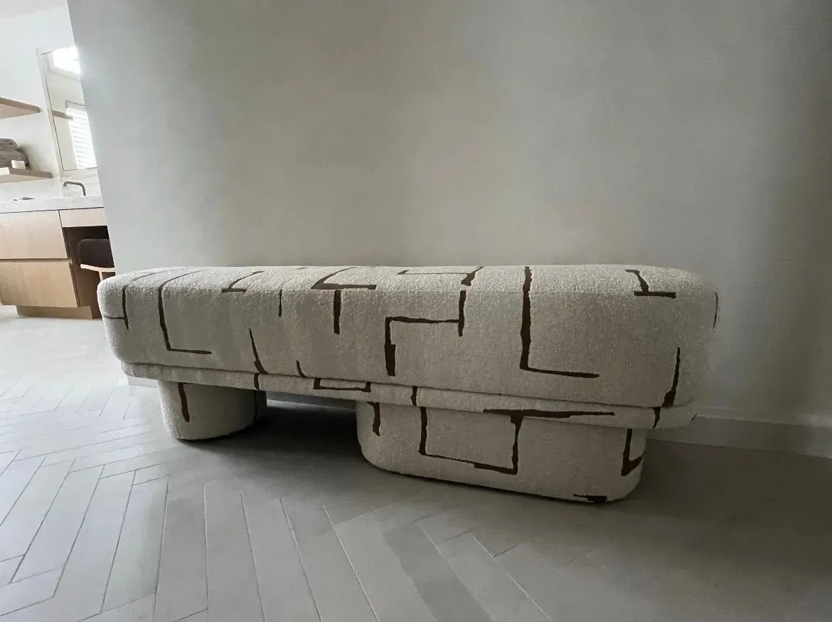 Cream upholstered bench with geometric pattern in a minimalist room