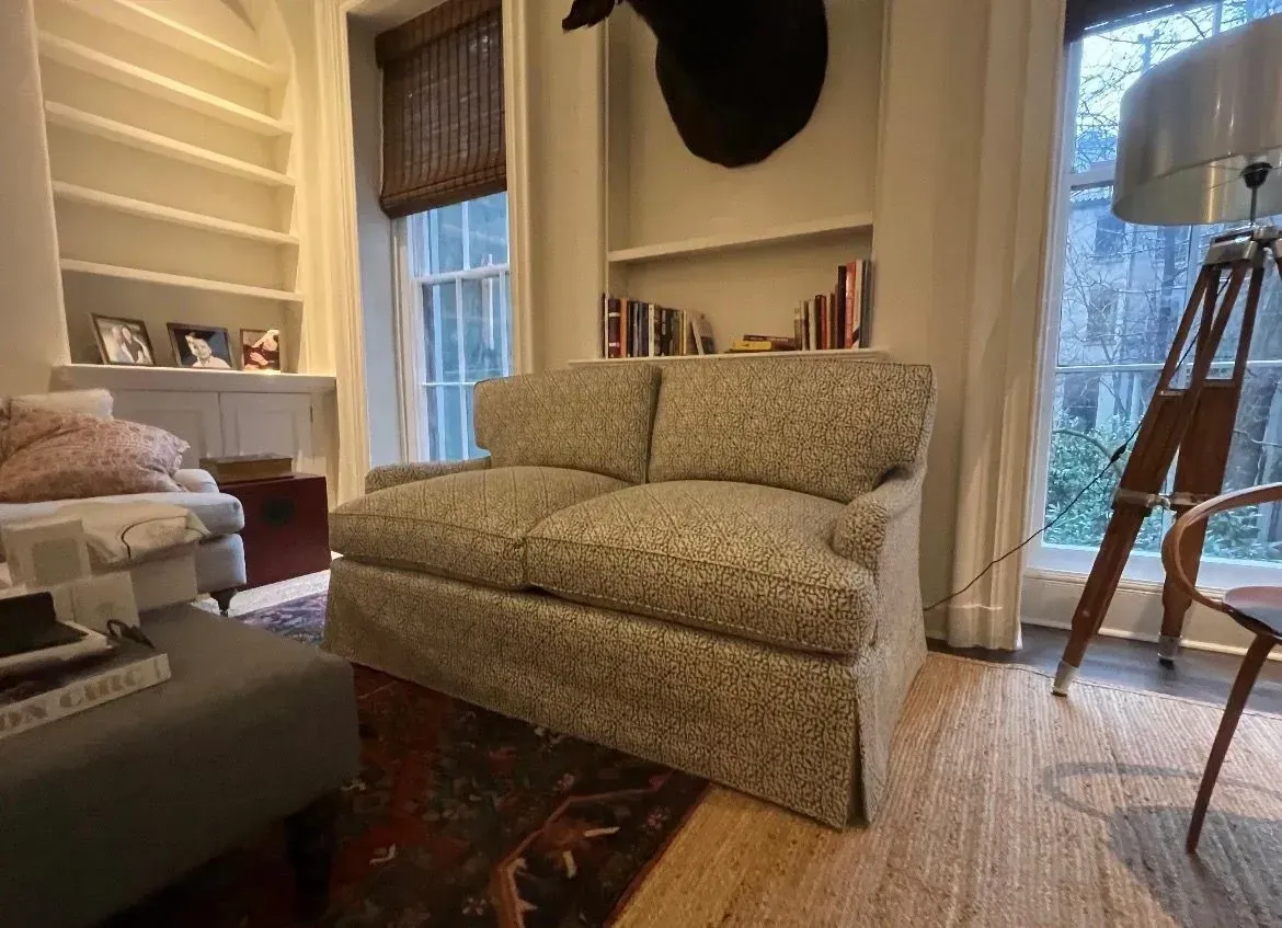 Cozy living room with patterned loveseat, window, wood floor, and floor lamp by the side table