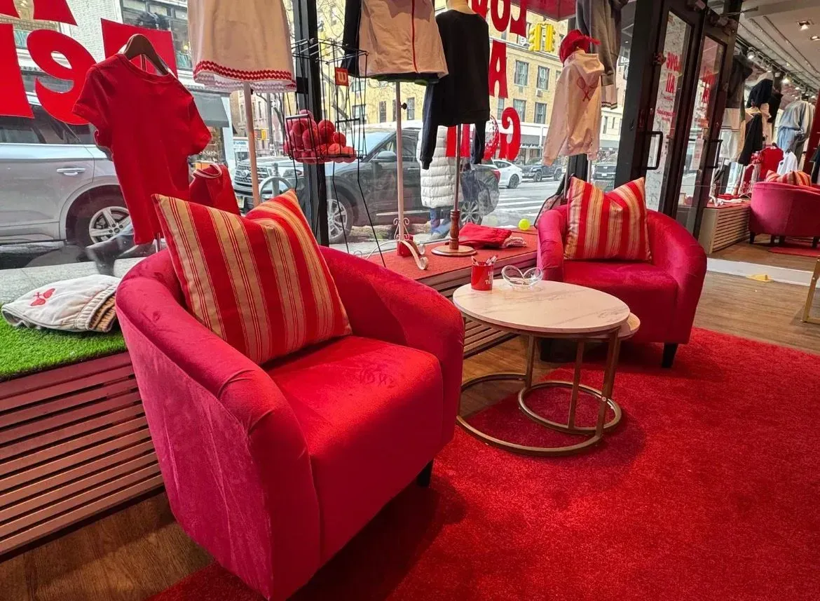Red lounge chairs with striped pillows and a small table on a red carpet in a storefront display