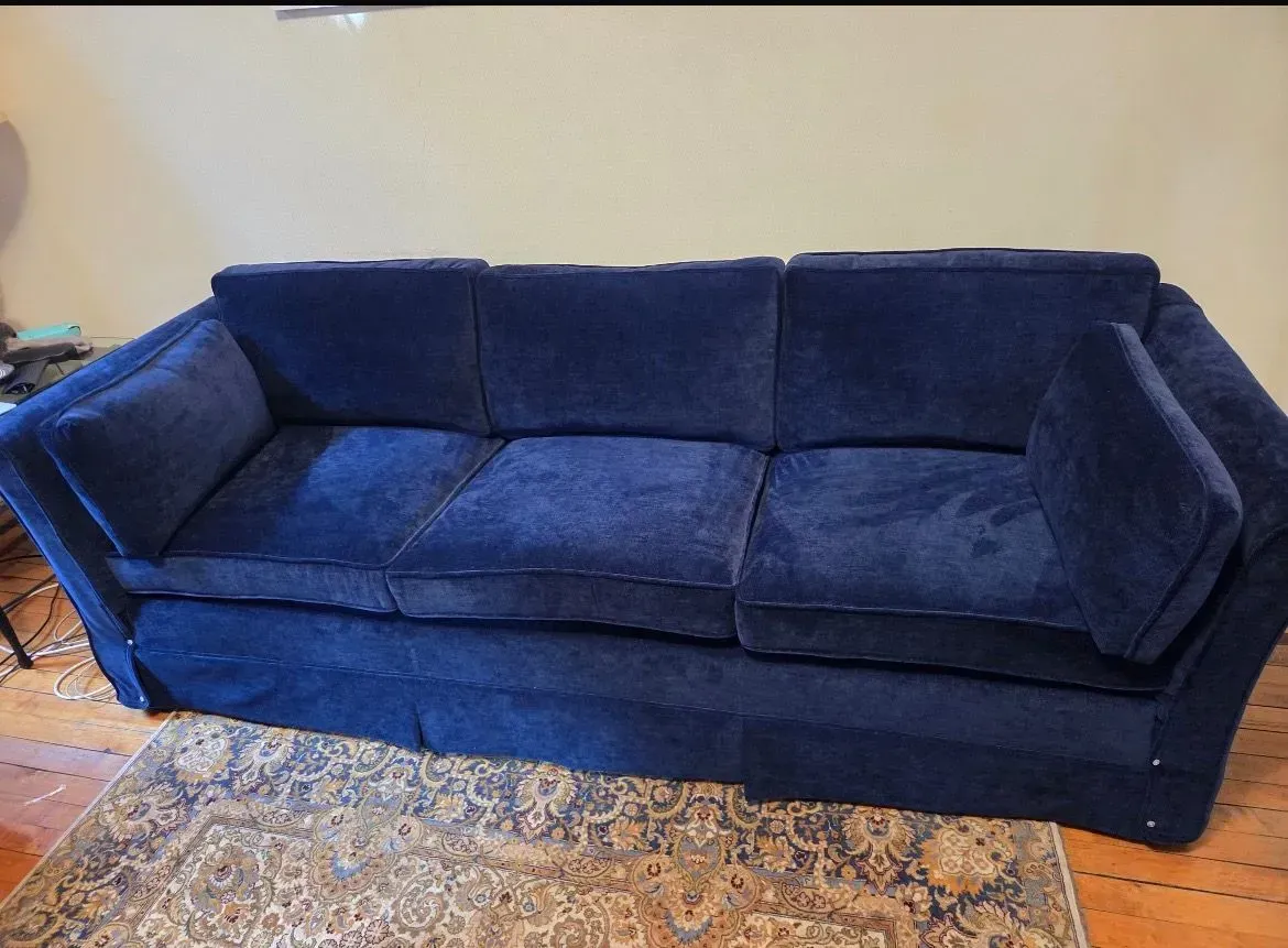 Blue velvet sofa on a patterned rug in a living room