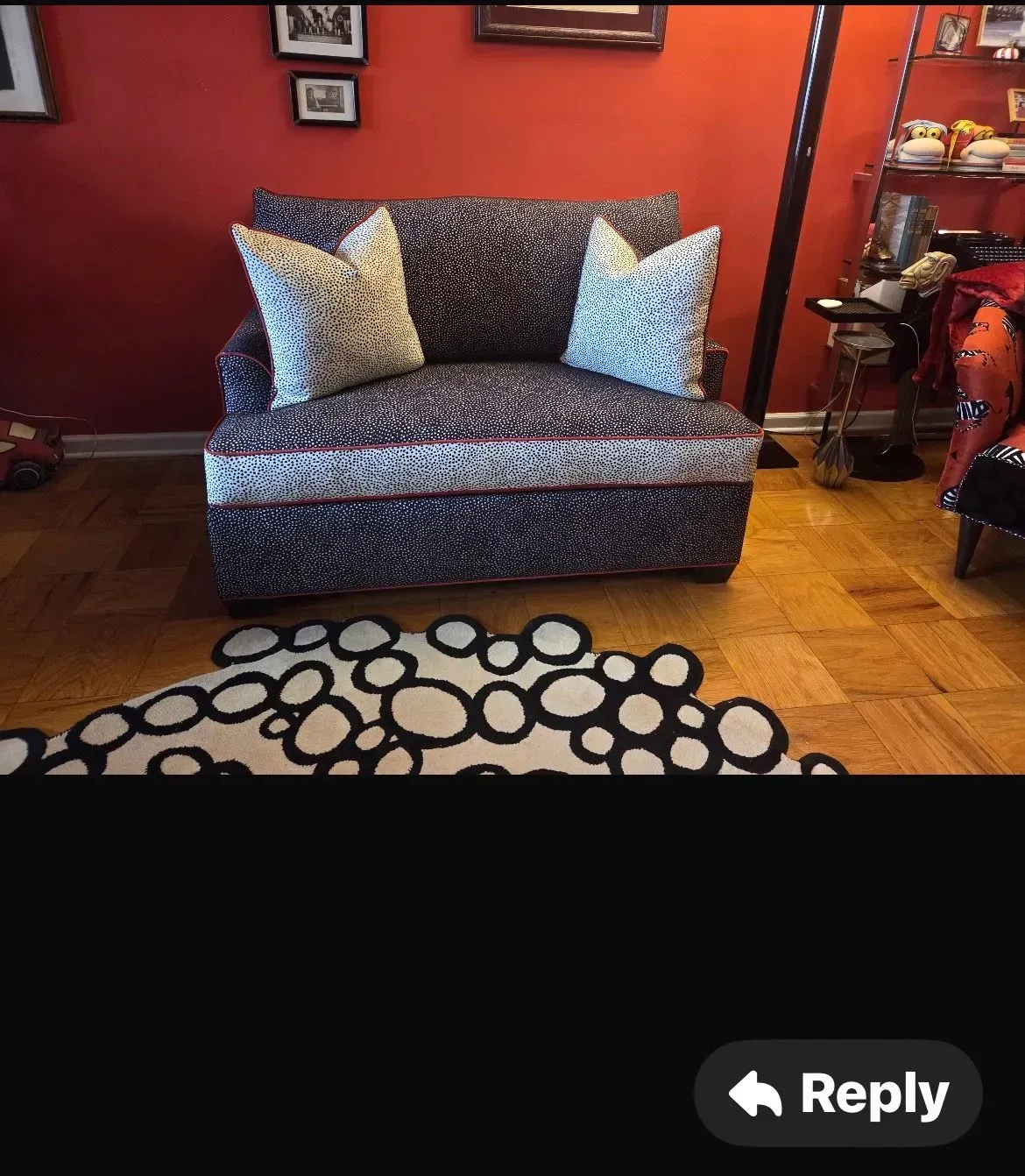 Patterned loveseat against red wall with framed art, hardwood floor, and circular rug in foreground
