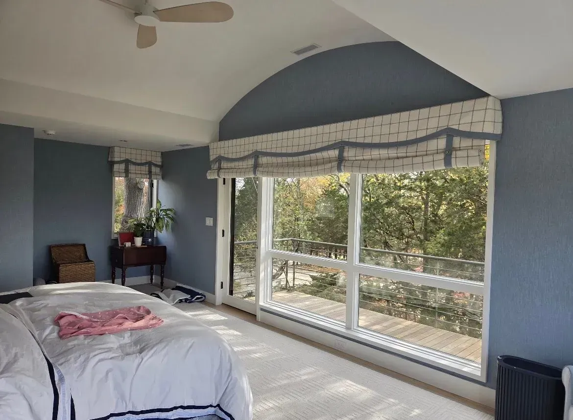 Bedroom with blue walls, large window, white bed, and a small desk by the window.