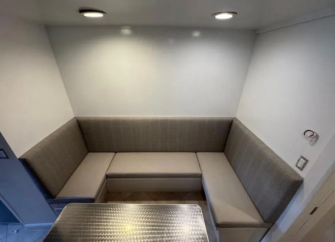 Small upholstered booth seating around a metal table in a bright, empty room with recessed lights.