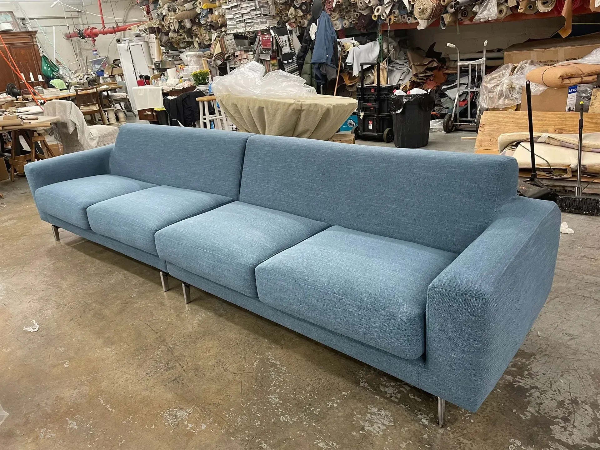 Light blue three-seat sofa in a workshop or warehouse setting