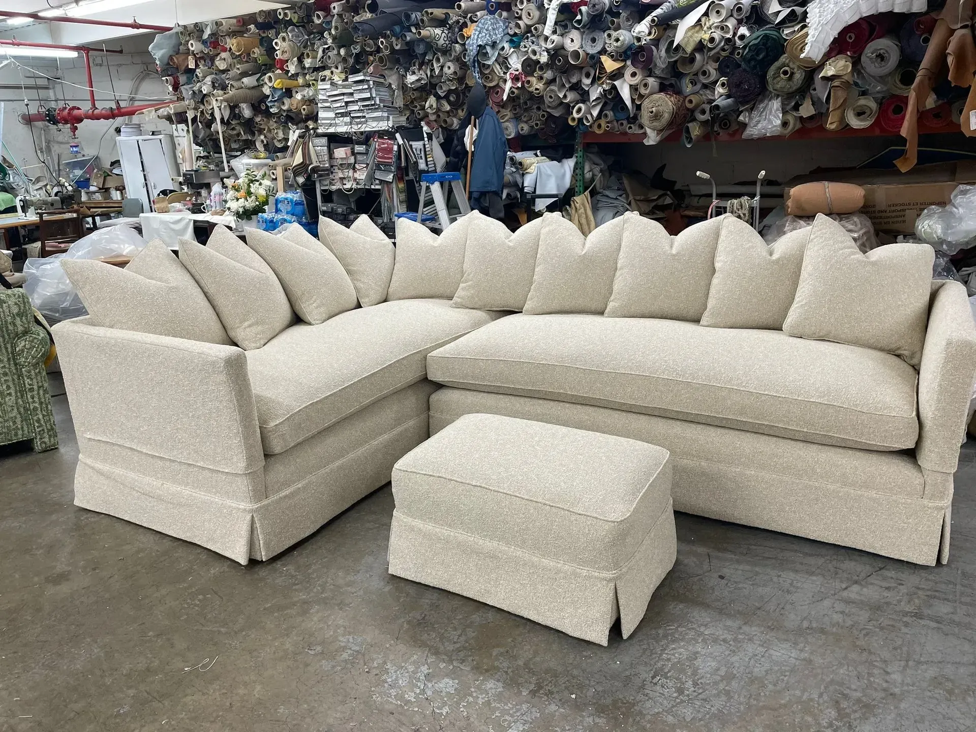 Cream-white sectional sofa with matching ottoman in a furniture warehouse showroom