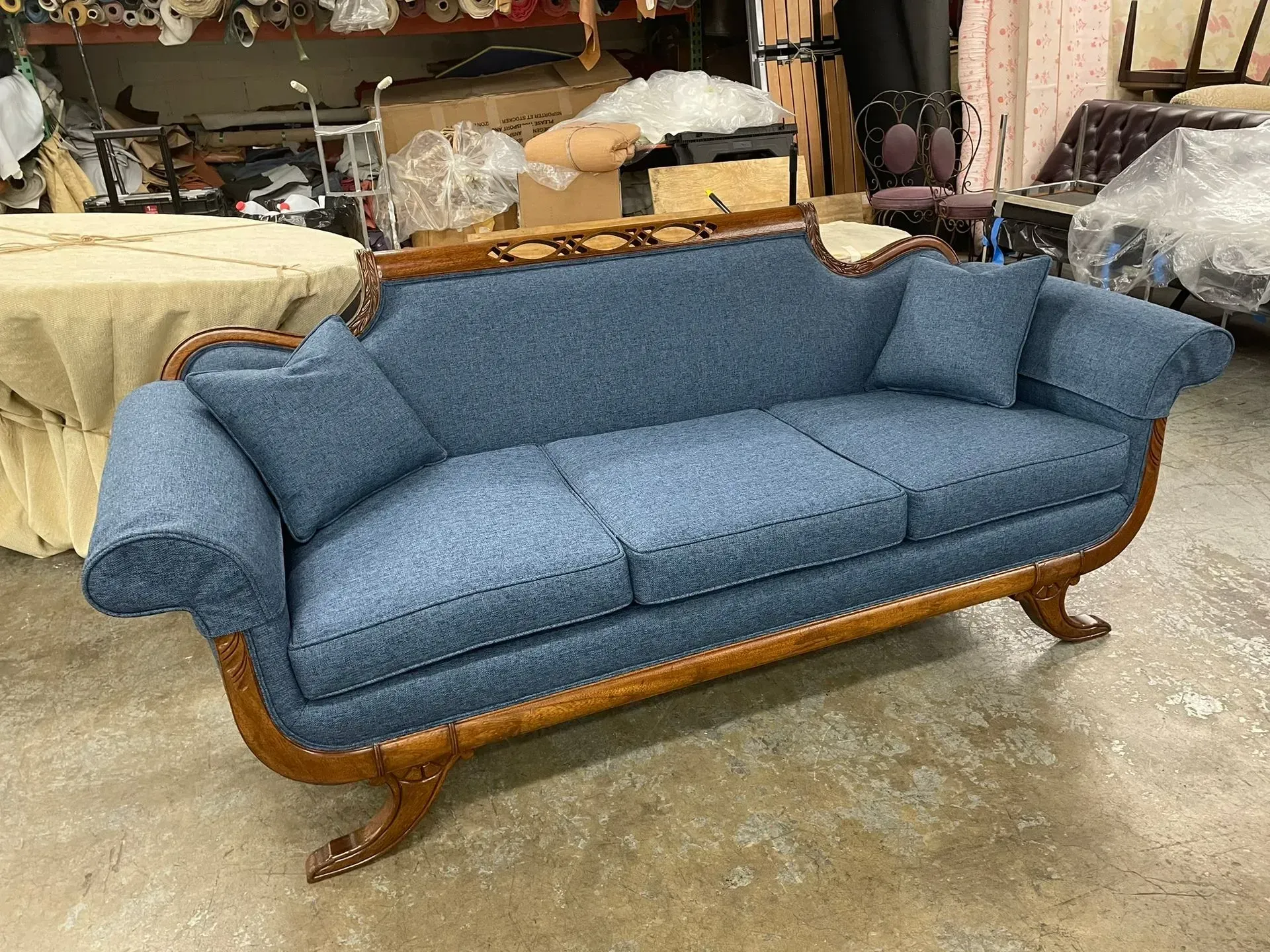 Blue upholstered sofa with wooden frame in a workshop or storage area