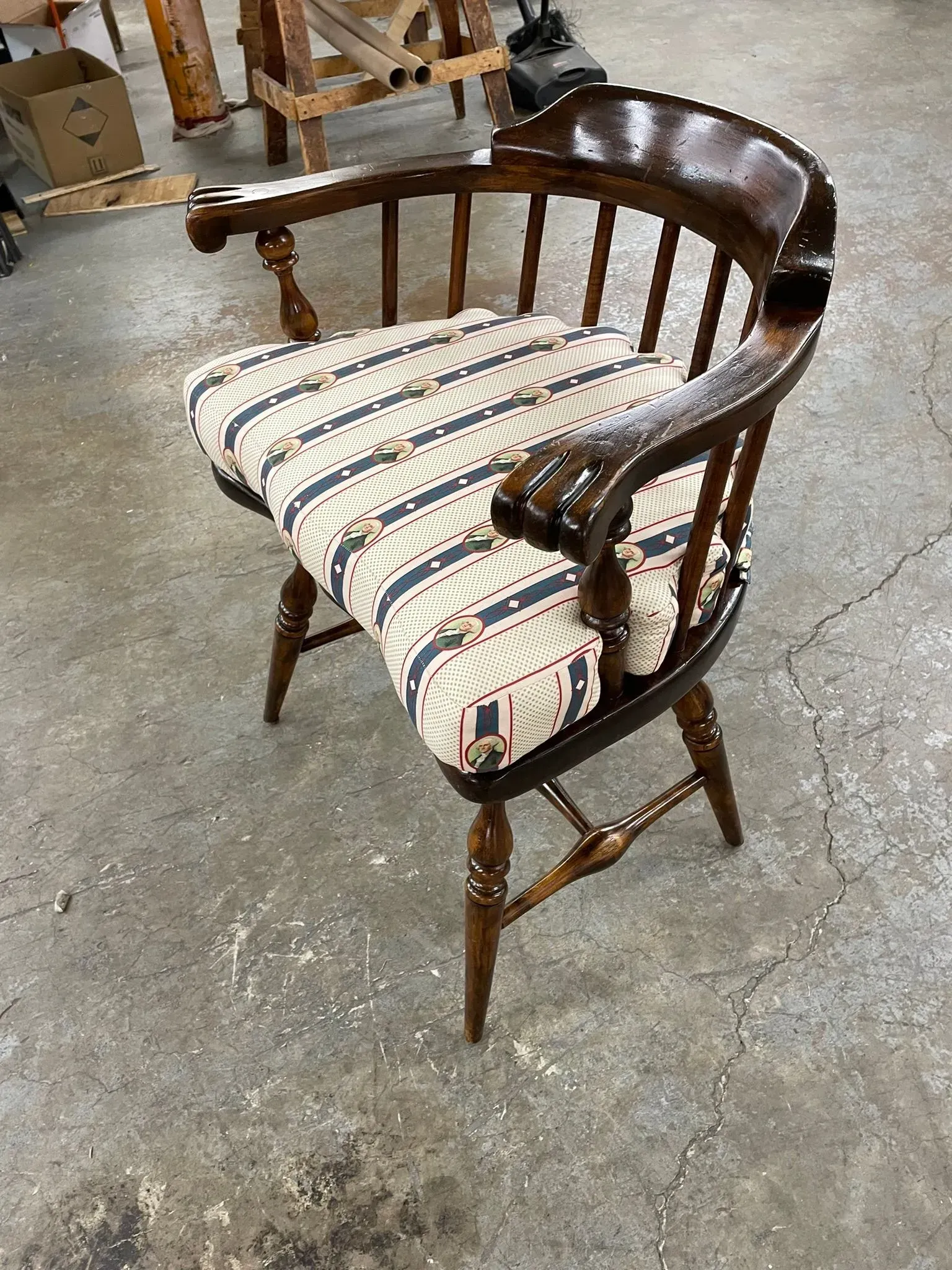 Dark wooden chair with striped upholstered seat and back in a workshop setting