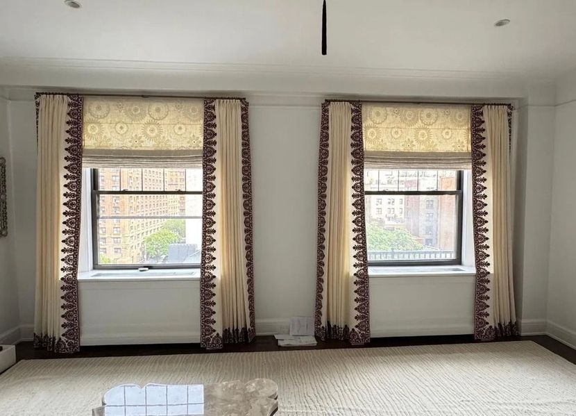 Bright empty room with two windows, patterned curtains, and white walls.