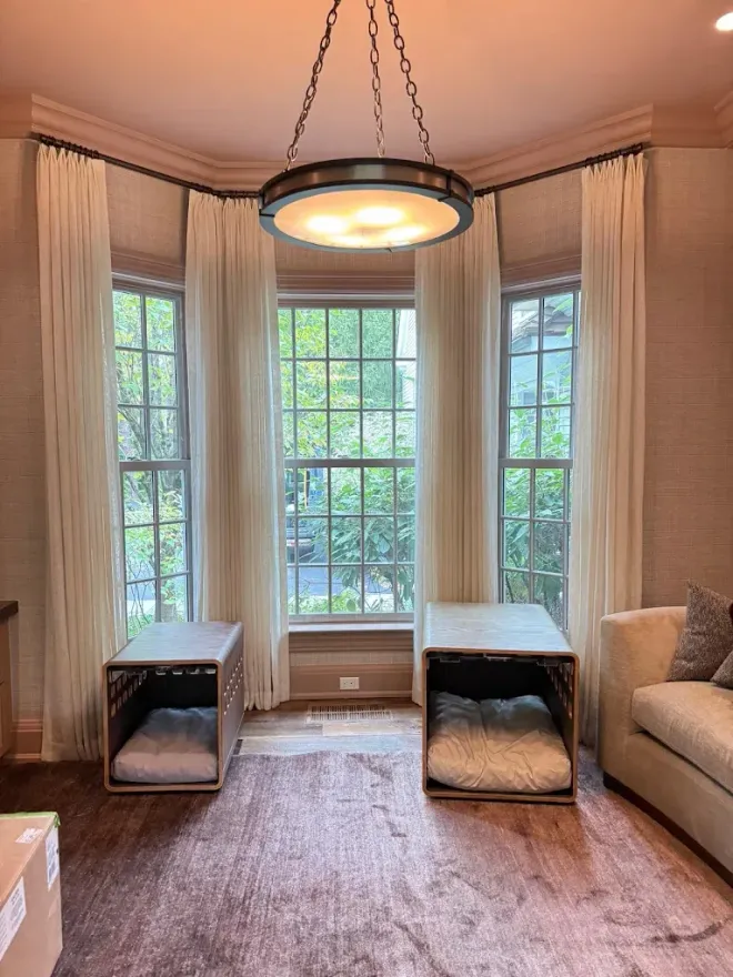 Bright bay window seating nook with sheer curtains, soft rug, and hanging light fixture