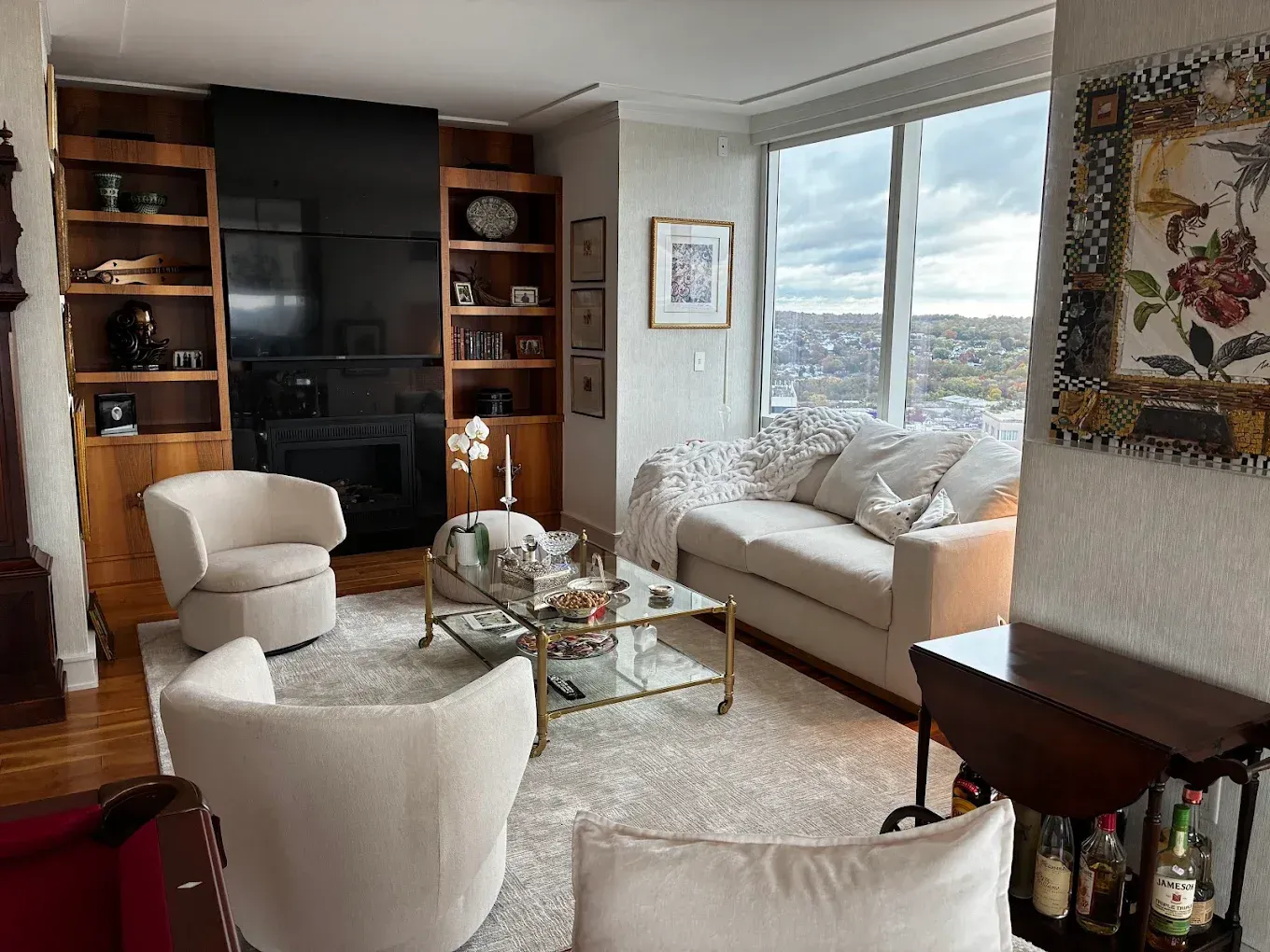 Elegant beige bedroom with a tufted bed, white linens, rust accent runner, and framed wall art.