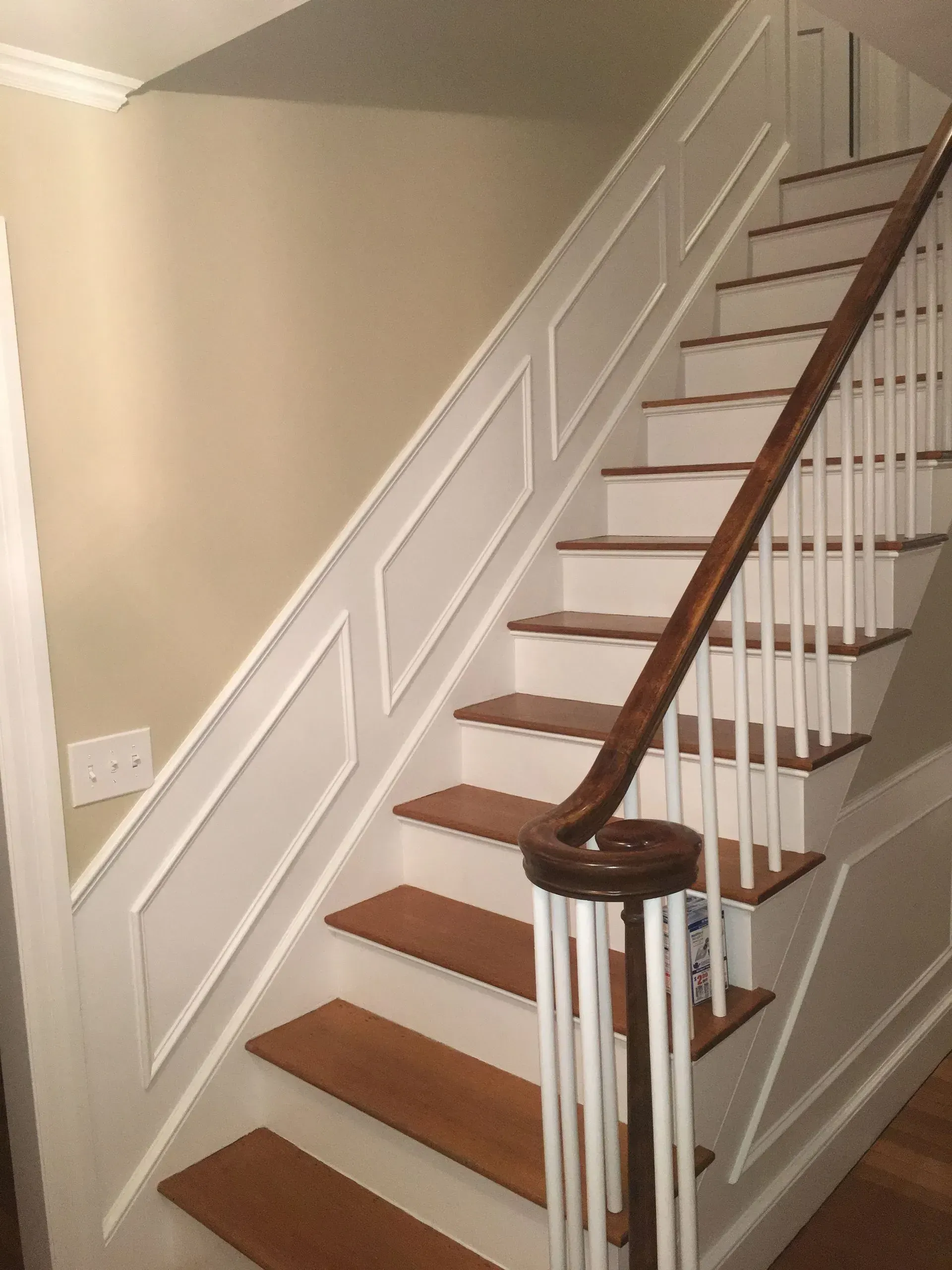 Indoor staircase with white railings, brown wooden steps, and beige walls