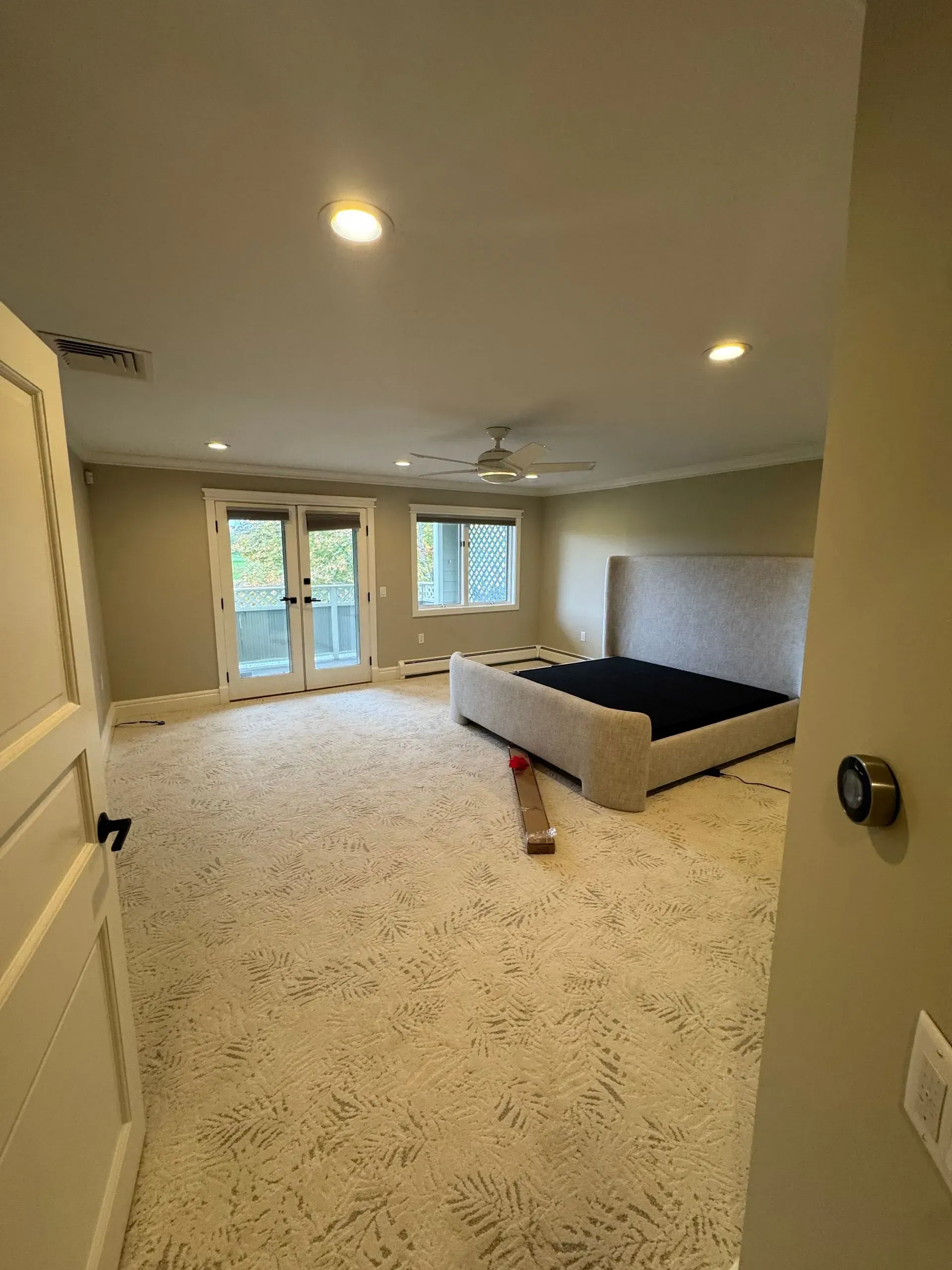 Empty bedroom with carpet, recessed lights, French doors, and a low bed frame against the wall