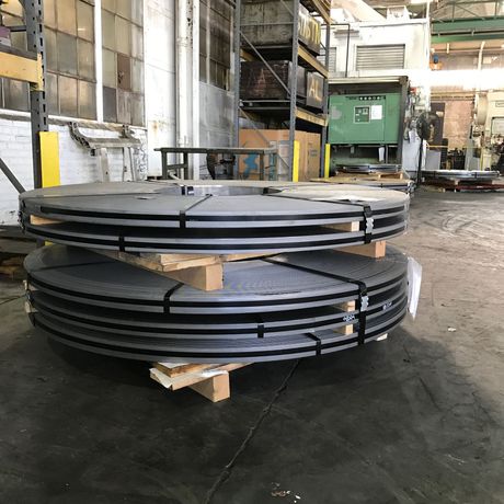 Stacked black metal rings on wooden blocks in an industrial warehouse.