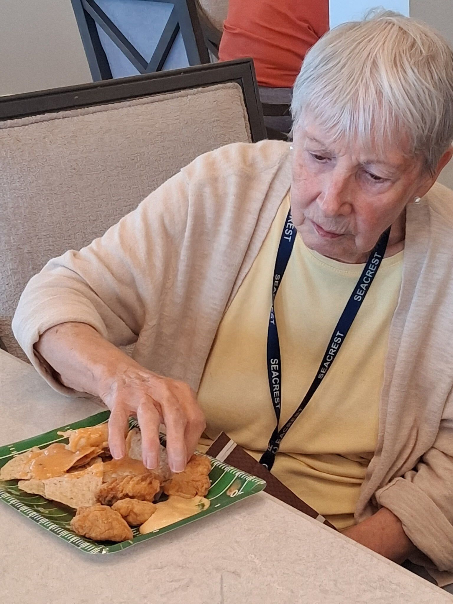 Older adult eating from a plate at a cafeteria table