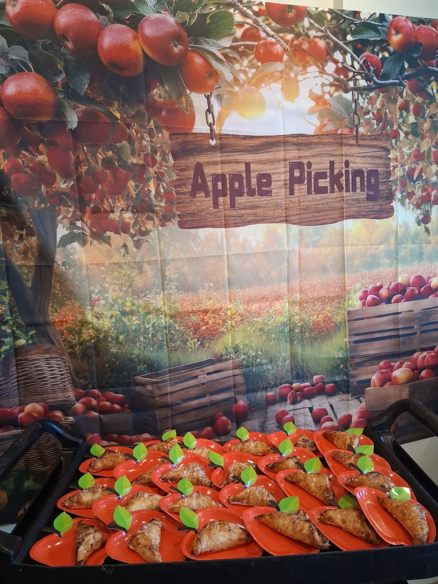 Apple picking display with red apples, baskets, and a harvest-themed sign in warm sunlight