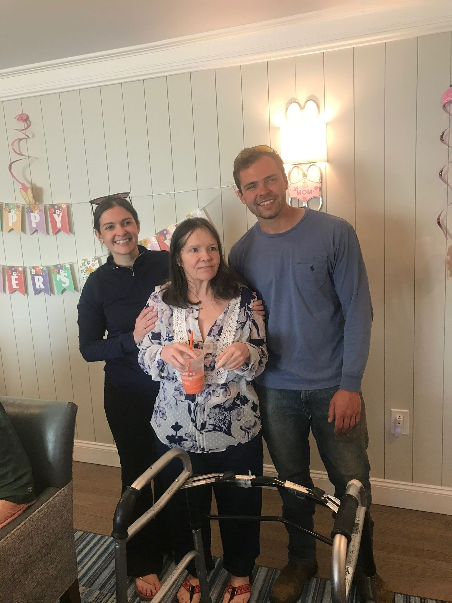 Three people pose together. A person uses a walker.  A 