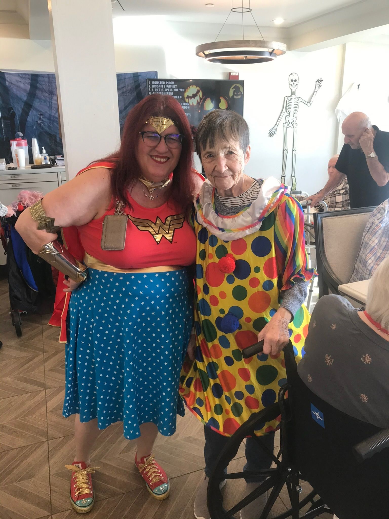 Woman dressed as Wonder Woman stands next to person in a clown costume. Both smile.