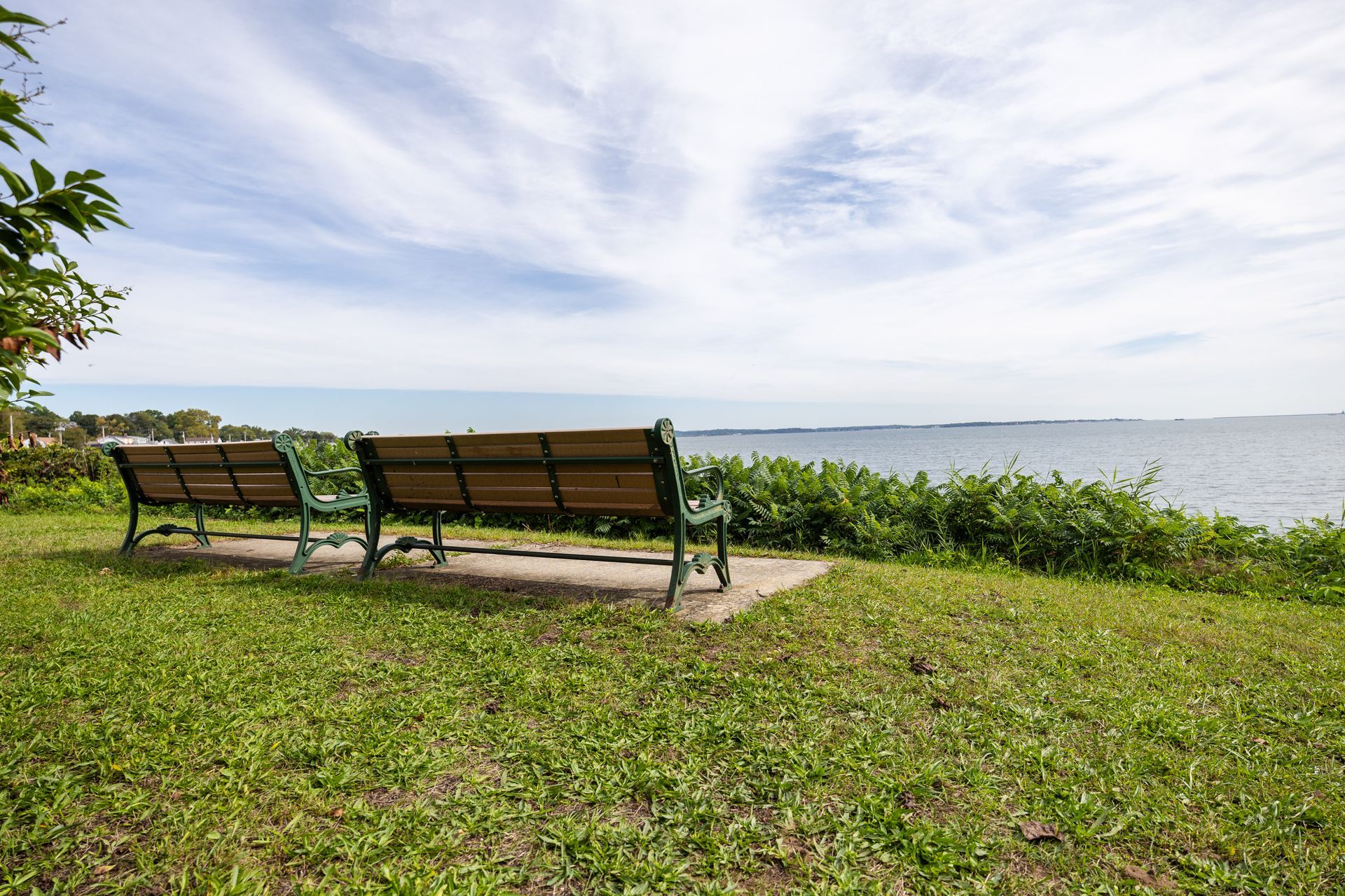 Two benches overlooking a body of water under a cloudy sky.