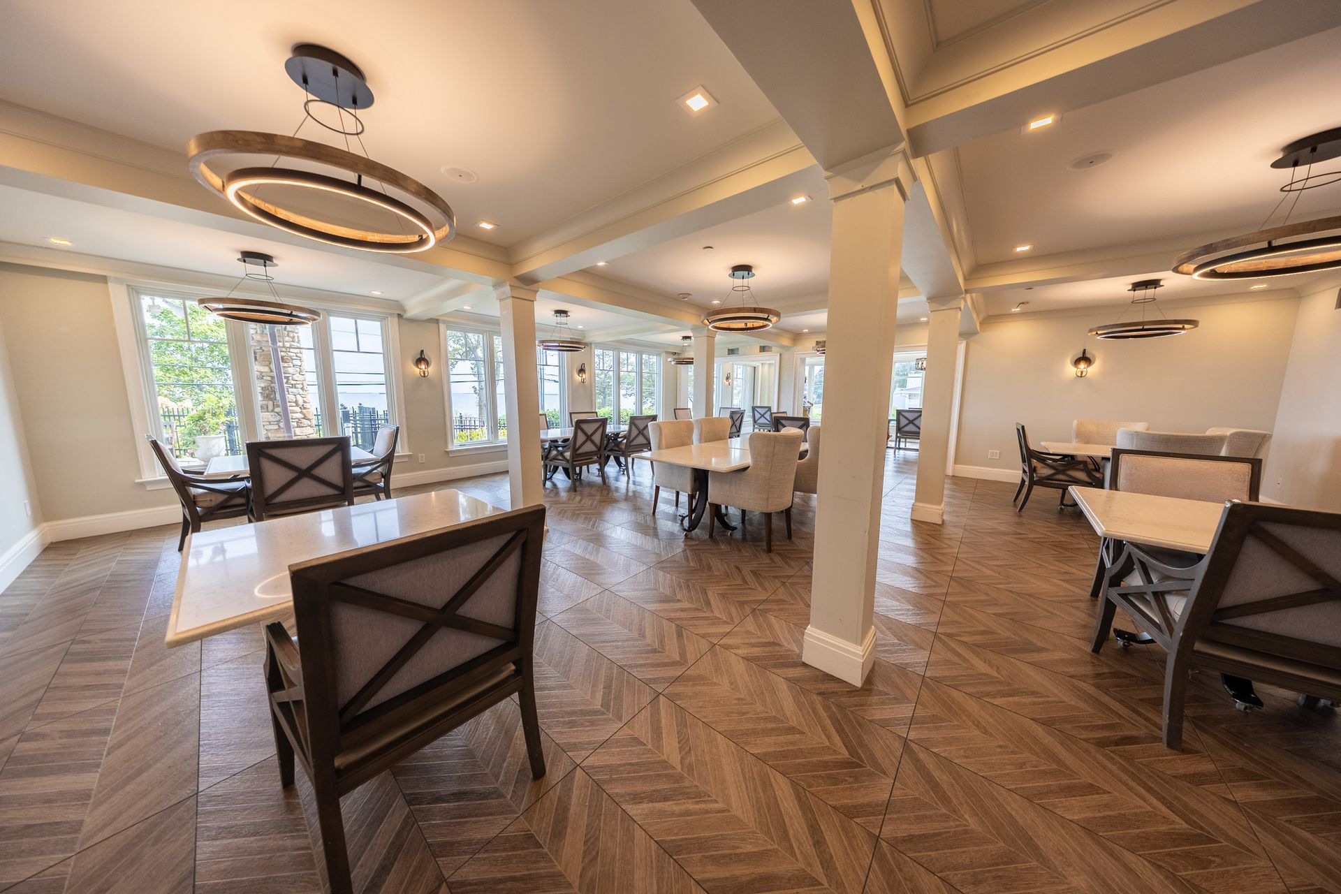 Dining room with wooden parquet floors, tables, chairs, and circular chandeliers.