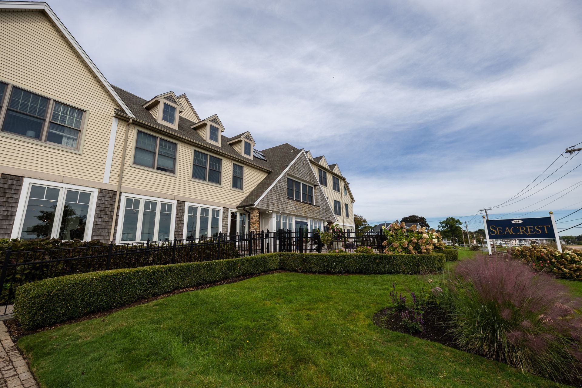 Beige building with dormers and green lawn.