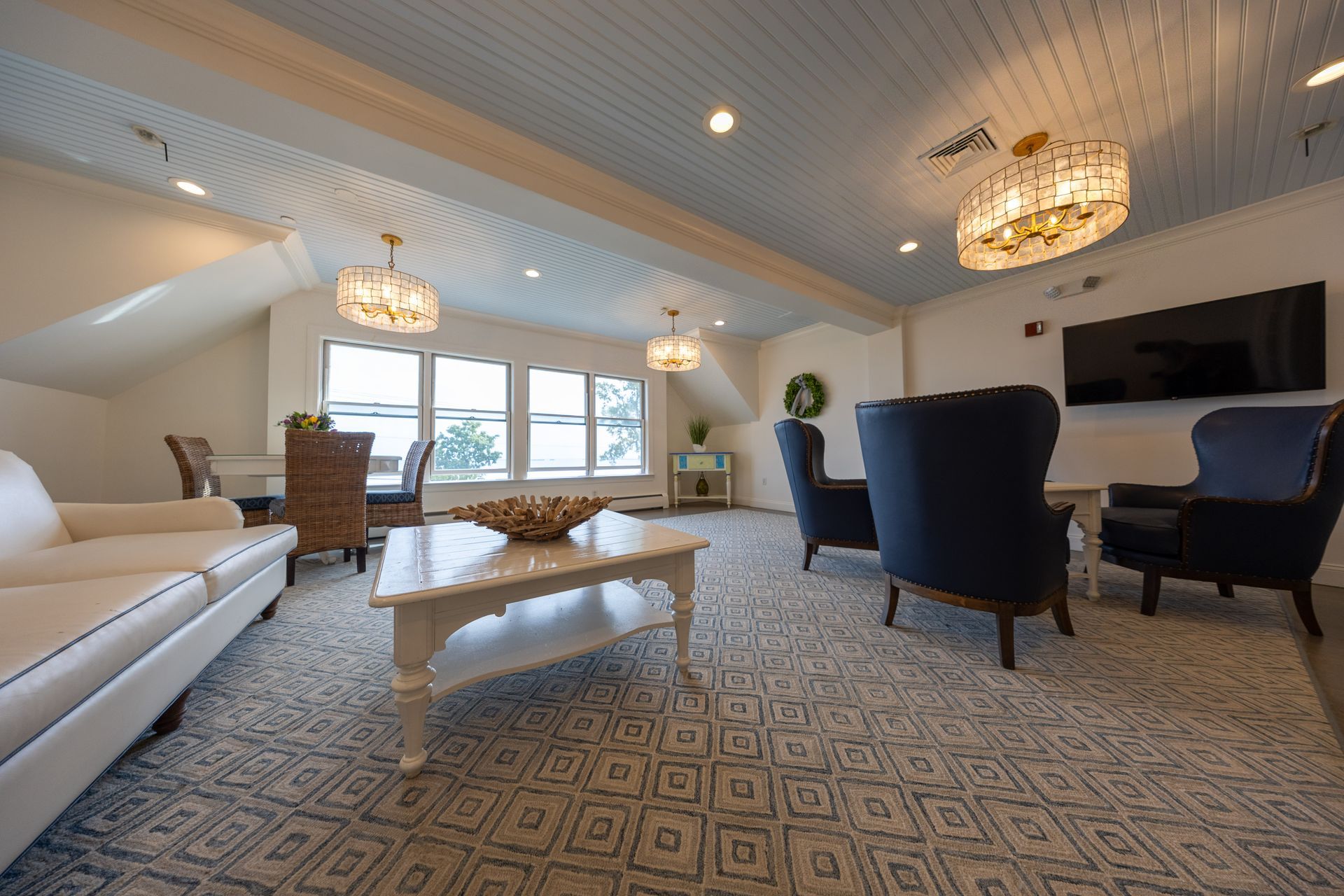 Living room with couches, chairs, coffee table, TV, and crystal chandeliers.