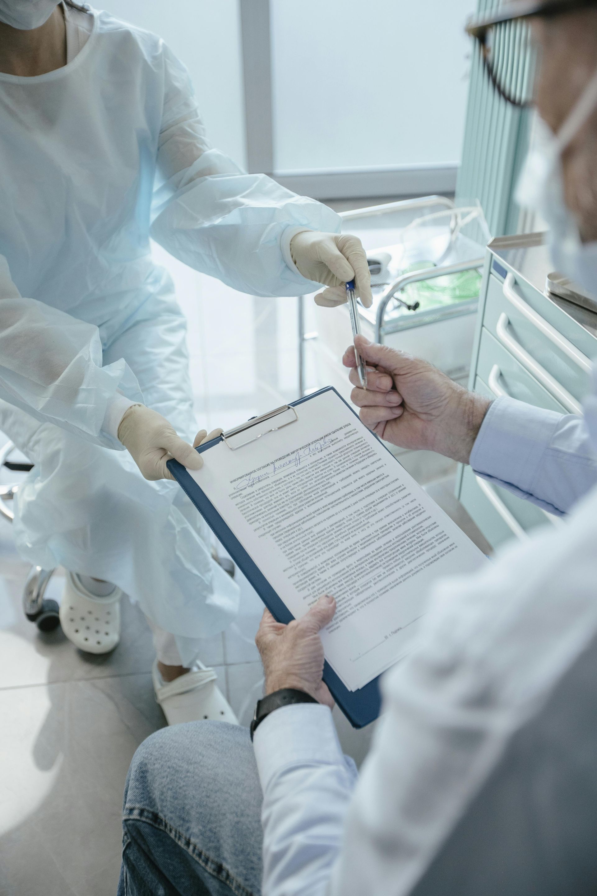 Medical personnel preparing to administer a shot, with a clipboard visible.