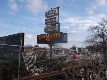 A sign for Ames Greenhouse featuring an electronic display reading