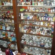 Wooden cabinets filled with numerous shelves packed with ceramic figurines, teacups, and small collectibles.