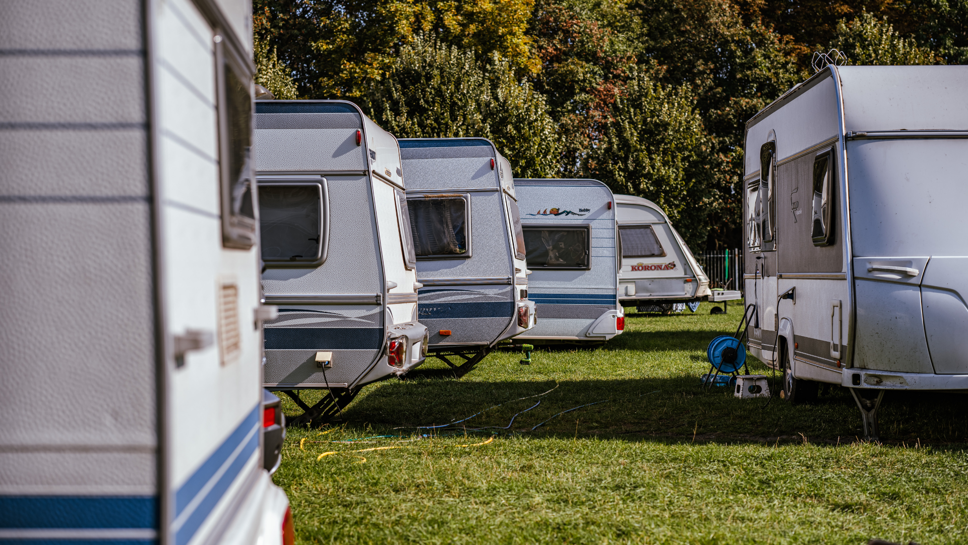 Several white and gray campers parked on grass.