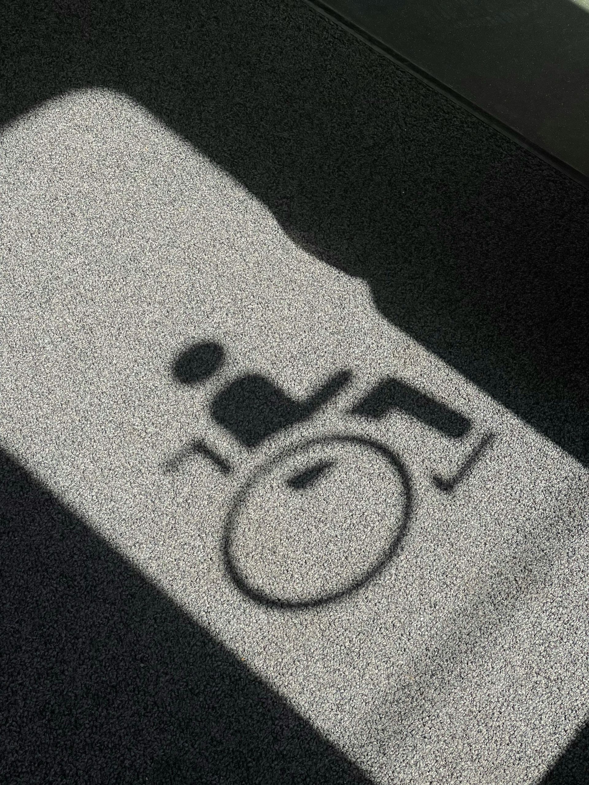 Bathroom stall door with a black baby changing table icon on a light sign.