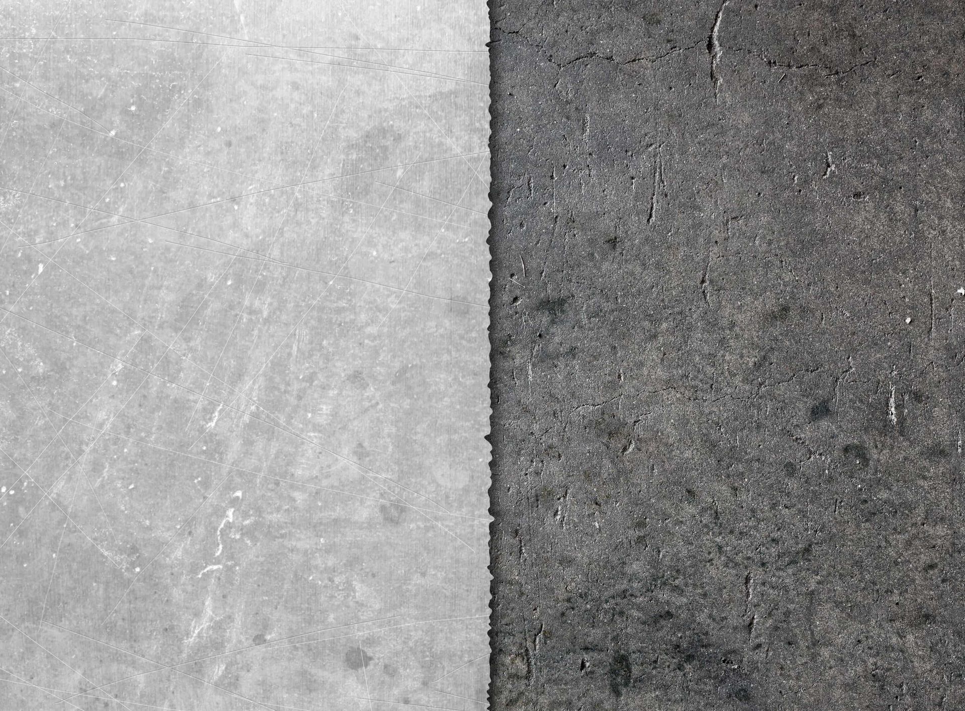 A close-up of a divided surface: left side is a light, worn gray, right side is dark gray asphalt.