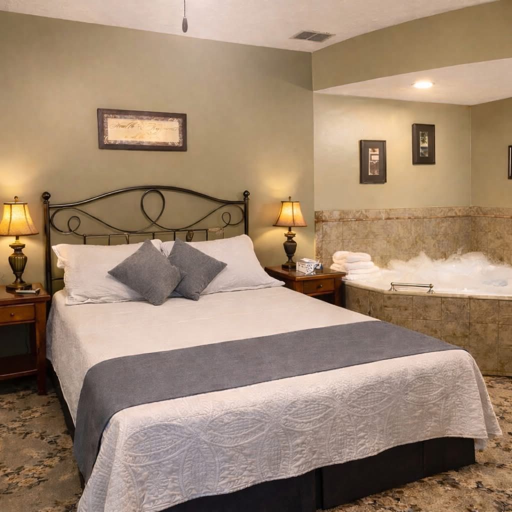 Bedroom with a neatly made bed, bedside lamps, and a corner soaking tub with bubbling water