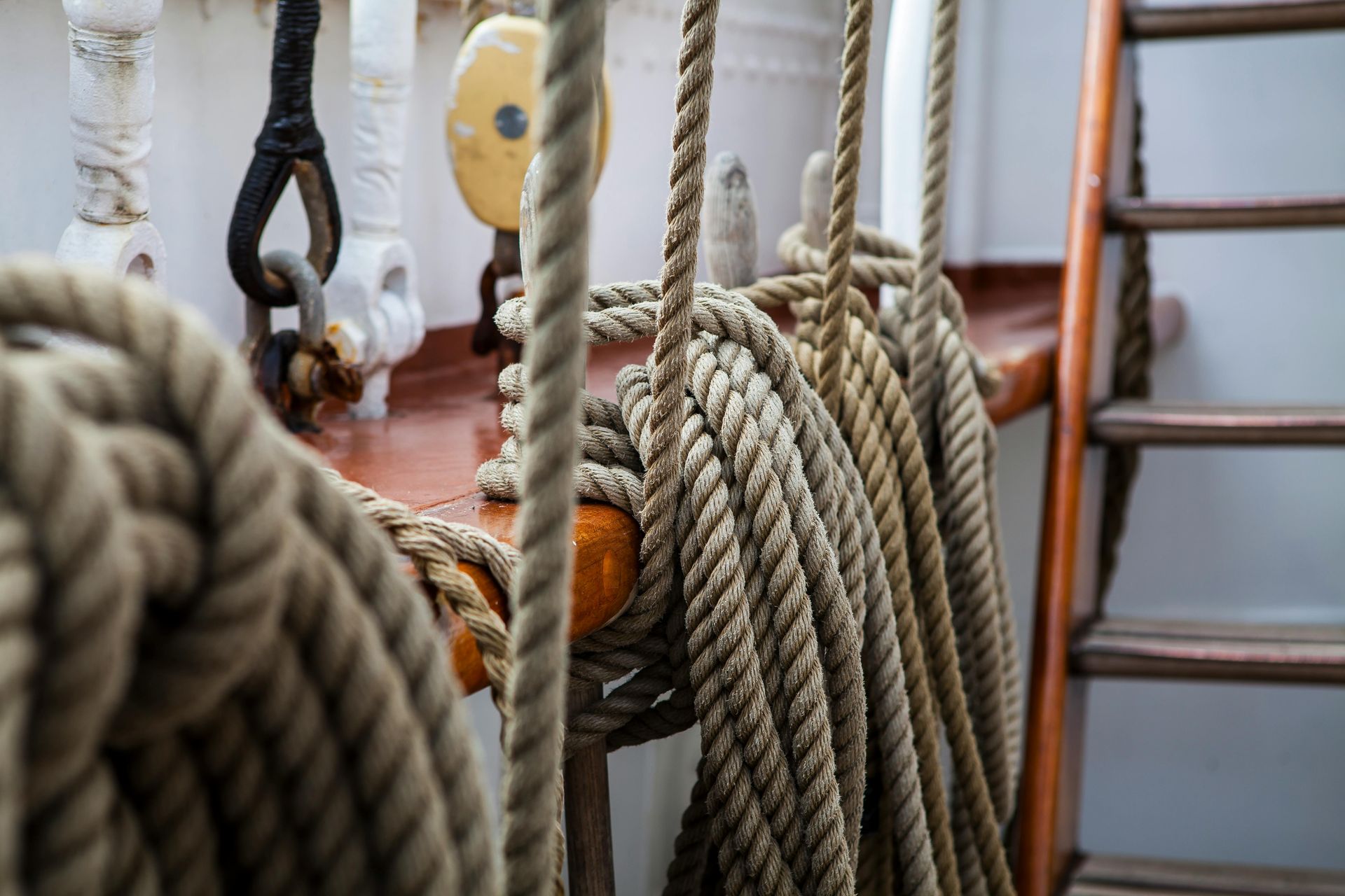 Coiled thick rope on a wooden boat deck beside a ladder and railing