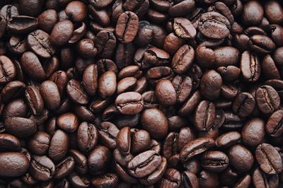 Dark roasted coffee beans piled closely together in a textured close-up.
