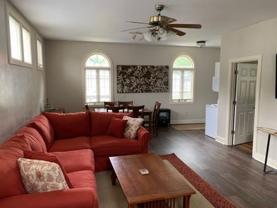 Living room with red sectional sofa, wooden coffee table, ceiling fan, and arched windows.