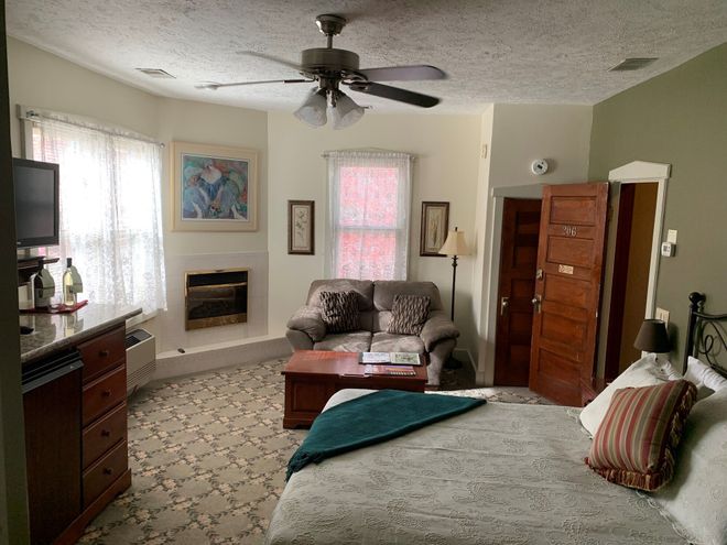 Cozy bedroom with a bed, fireplace, dresser, ceiling fan, and natural light from window curtains