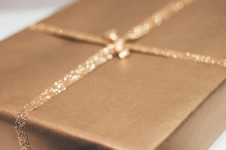 Wrapped gold gift box with glittery ribbon and bow