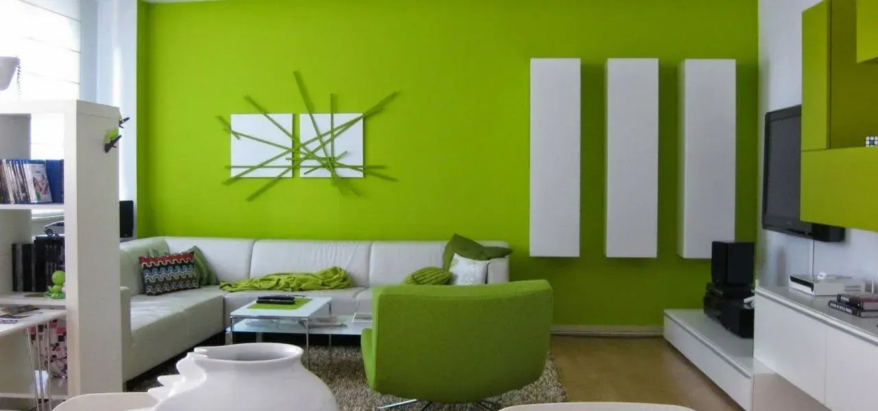 Un soggiorno moderno con una parete verde brillante, un divano bianco e una poltrona verde.