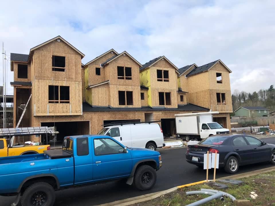 A blue truck is parked in front of a building under construction.
