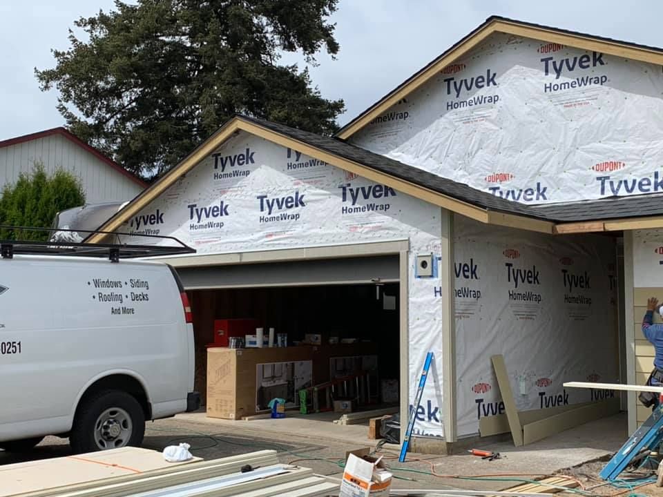 A white van is parked in front of a house under construction.