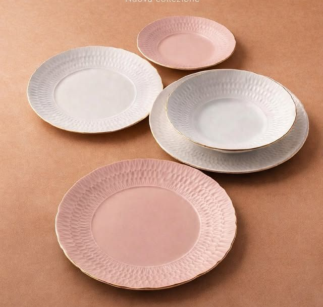 Quattro piatti decorativi dai colori pastello disposti su una superficie color beige.