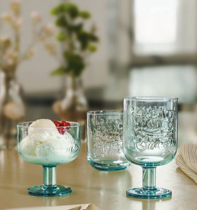 Su un tavolo, tre bicchieri turchesi riccamente decorati, uno dei quali contiene un dessert guarnito con frutti di bosco.