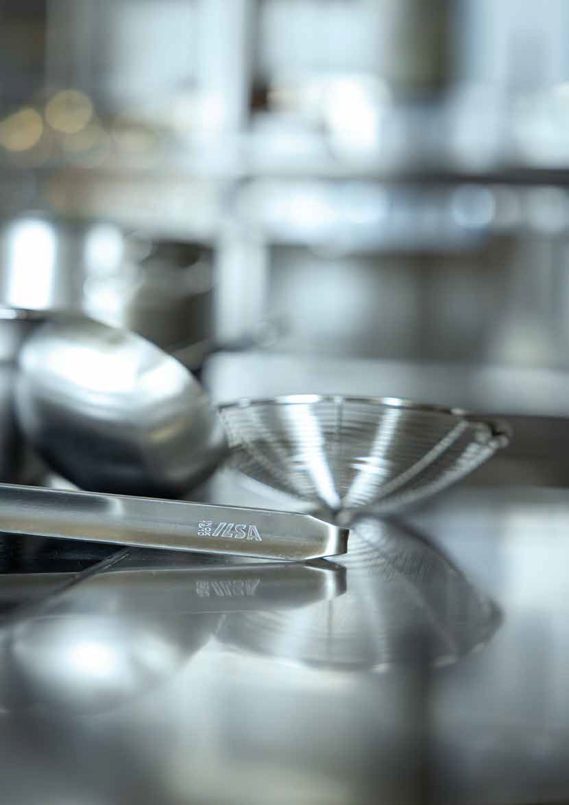 Cucchiai dosatori in metallo su un piano di lavoro da cucina riflettente con uno sfondo sfocato